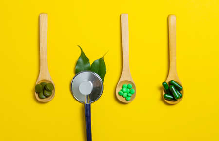 Mixed herbal tablets on a wooden spoon. Food supplement.の写真素材
