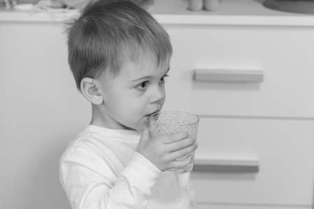 The child drinks water from a glass.の写真素材