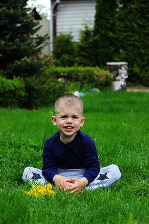 little boy sits on the grass. Selective focusの写真素材
