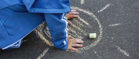 Cute little child draws the sun with chalk outdoors, summer time, chalk. Selective focus. Natureの写真素材