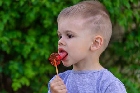 Photo of a boy with a lollipop on a green background. Nature. Selective focusの写真素材