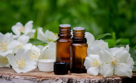 Essential oil and jasmine flowers on a wooden background. Cosmetic procedures. Selective focusの写真素材