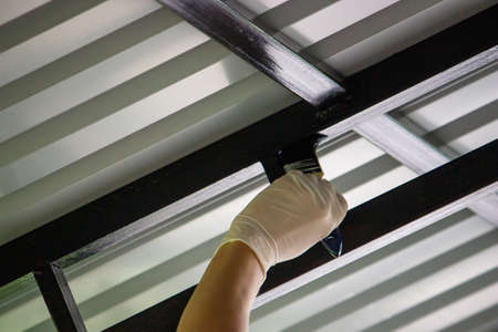 girl paint with a brush black metal. paints the roof. Selective focusの写真素材