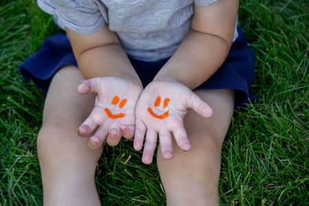 The child was lying on the green grass. Smile with paints on the legs and arms. Child having fun outdoors in the spring park. Selective focus. Natureの写真素材