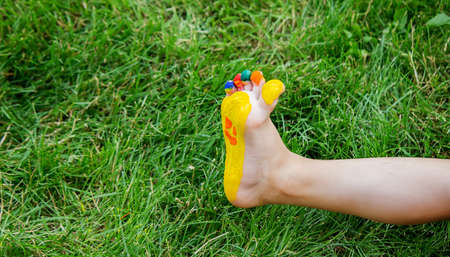 The child was lying on the green grass. Smile with paints on the legs and arms. Child having fun outdoors in the spring park. Selective focus. Natureの写真素材