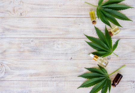 cannabis leaves on wood background with bottles, cannabis oil. Selective focusの写真素材