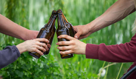 The hand of a man holding a beer bottle in nature. rest by the river. Nature. Selective focusの写真素材