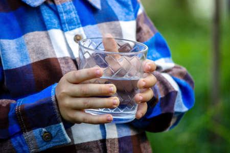 water in a glass in the hands of a child and father. Nature. Selective focusの写真素材