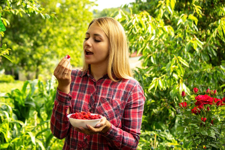 girl holding a bowl with organic product of ripe raspberries on the farm. Selective focusの写真素材