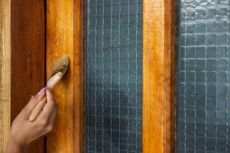 Beautiful young girl paints a wooden door. Summer work in the garden. Selective focusの写真素材