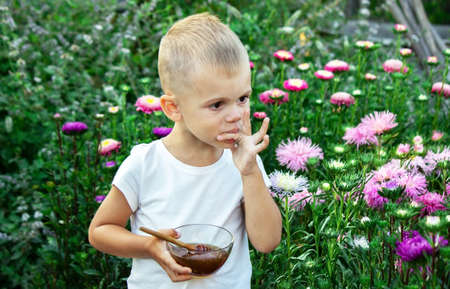 A child eats honey in a flower garden. Nature. Selective focusの写真素材