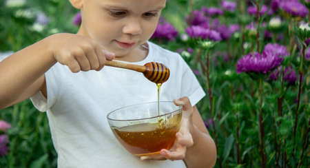 child eats honey in the garden. Selective focusの写真素材