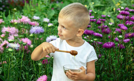 child eats honey in the garden. Selective focusの写真素材