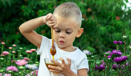child eats honey in the garden. Selective focusの写真素材