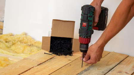 the man twists the screws into the board. Repair of the floor in the house. Selective focus. Interの写真素材