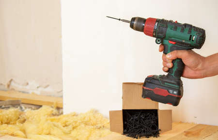 the man twists the screws into the board. Repair of the floor in the house. Selective focus. Interの写真素材