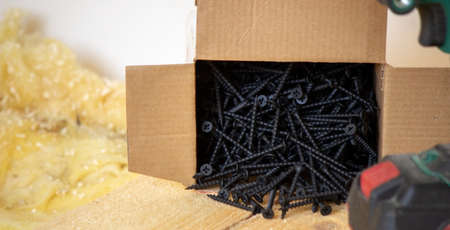 A man makes repairs in the house, a screwdriver, screws, a saw. Wooden floor. Selective focusの写真素材