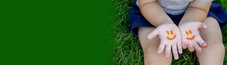 The child was lying on the green grass. Smile with paints on the legs and arms. Child having fun...
