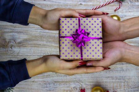 New Year's gifts in hands on a wooden background. Christmas selective focusの写真素材