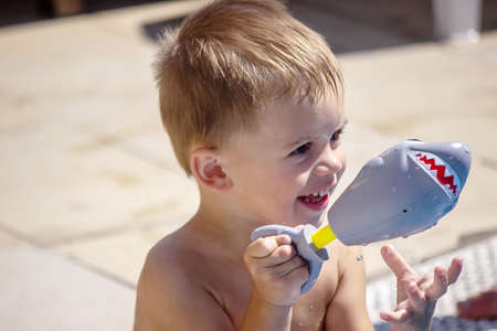 Happy child in the pool playing with a water gun. Recreationの写真素材