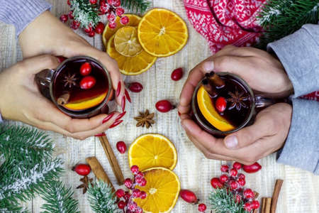 Hot mulled wine in female hands, spices on weathered wooden table. Sweet-home conceptの写真素材