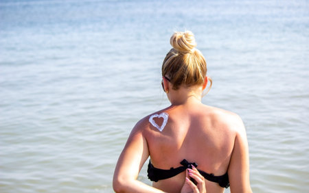 painted heart on the girl's back with sun cream. Rest by the sea