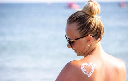 painted heart on the girl's back with sun cream. Rest by the seaの写真素材