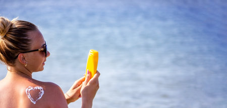 painted heart on the girl's back with sun cream. Rest by the seaの写真素材