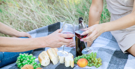 picnic in nature, a girl and a man are holding glasses in their hands with wine. Selective focus