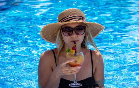 girl drinks a cocktail in the pool. selective focus