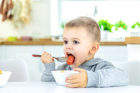 children in the kitchen at the table turning pasta. selective focusの写真素材