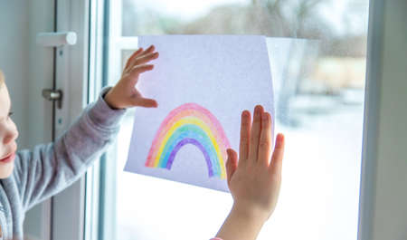 drawn rainbow on a sheet. Children hold a leaf with a rainbow near the window. selective focusの写真素材