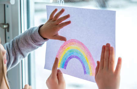 drawn rainbow on a sheet. Children hold a leaf with a rainbow near the window. selective focusの写真素材