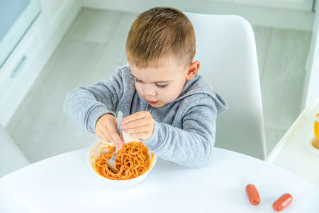 children in the kitchen at the table turning pasta. selective focusの写真素材