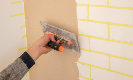 Hand with putty knife repair damaged wall. selective focusの写真素材