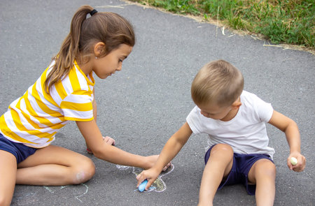 children draw on the pavement with chalk. very good weather. selective focus