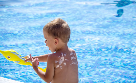 Mother puts cream on her son's back. baby skincare. travel sunscreen. selective focus