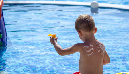 Mother puts cream on her son's back. baby skincare. travel sunscreen. selective focusの写真素材