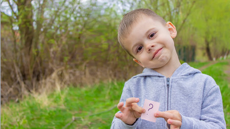 the boy holds stickers with a question mark on the background of the park. Nature. selective focus