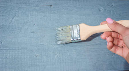 girl paints a board with a brush. Paint with gray paint. selective focusの写真素材