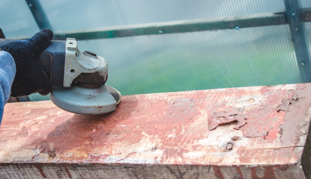a man is grinding a board. Removing old paint from boards. Carpentry work. selective focus