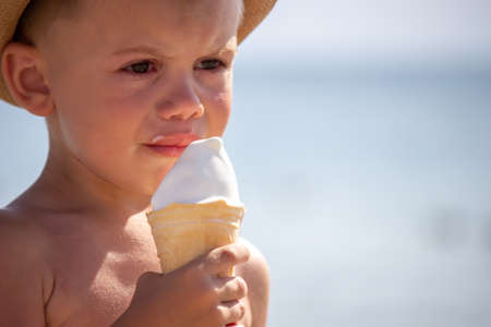 the child cries and eats ice cream on the beach. selective focusの写真素材