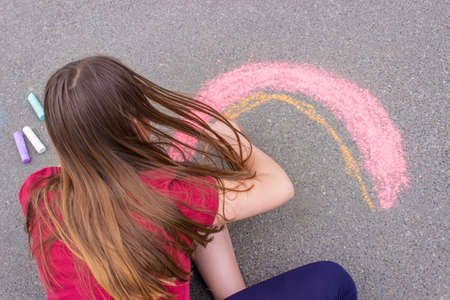 a girl draws a rainbow, a house with chalk on the pavement. selective focusの写真素材