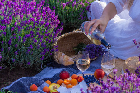 a girl in a lavender field pours wine into a glass. relaxation. selective focusの写真素材