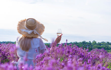 a girl in a lavender field pours wine into a glass. relaxation. selective focusの写真素材