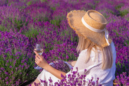 a girl in a lavender field pours wine into a glass. relaxation. selective focusの写真素材