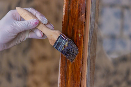 a hand holds a brush, applying varnish paint on a board - painting and caring for a tree. selective focusの写真素材