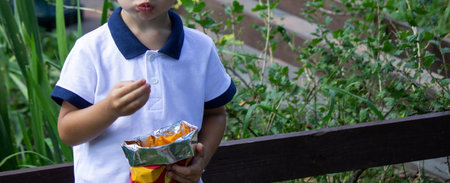 little boy eats potato chips from a pack. selective focus