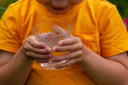 The child drinks water from a glass. Selective focus. Kid.の写真素材