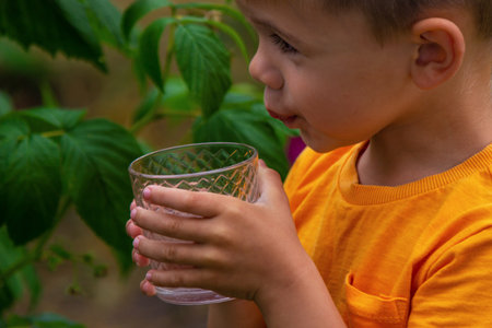The child drinks water from a glass. Selective focus. Kid.の写真素材